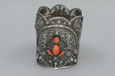 un vieux bracelet manchette aux couleurs argentées et corail, orné d'un motif floral