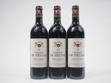 trois bouteilles de vin rouge posées l'une à côté de l'autre sur une surface blanche