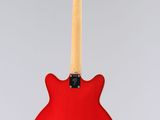 a red electric guitar hanging from a string on a gray background