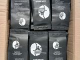 six bags of coffee sit in a cardboard box on a table