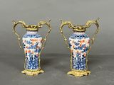 pair of blue and white vases with gold handles on a gray surface