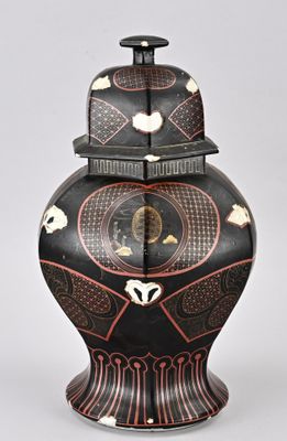 un vase noir orné d'un motif rouge et blanc