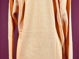 an orange sweater on a mannequin stand against a purple background