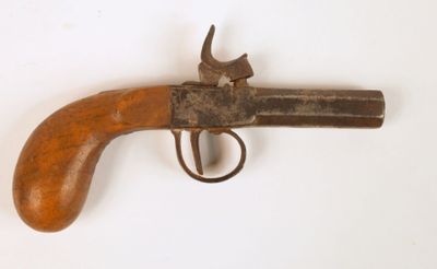 un vieux pistolet avec une poignée en bois sur une surface blanche