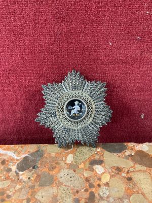 a small silver brooch on a red cushion