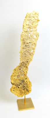 gold leaf sculpture on stand on white surface with white background