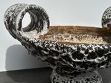 a black and white bowl with two handles on a black table
