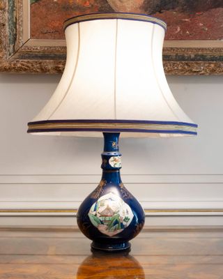 a lamp that is sitting on a table in front of a painting