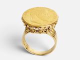 un gros plan d'une bague en forme de pièce d'or sur fond blanc