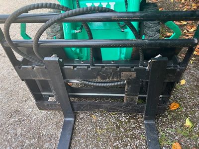 a fork lifter with a bunch of green containers on it
