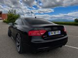 a black car parked in a parking lot with a cloudy sky in the background