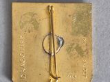 a gold pin with a key on it sitting on a piece of paper