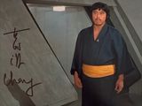 une photo d'un homme en kimono debout devant un mur