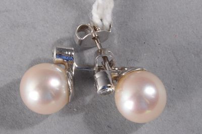 pair of white pearl earrings with blue stones on a gray surface