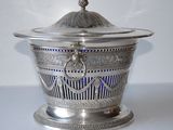 a silver bowl with a lid on a white table