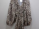 a leopard print robe hangs on a hanger against a wall