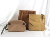 three pieces of leather bags sitting on top of a white surface
