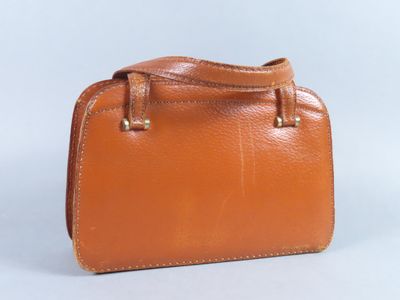 un porte-monnaie en cuir marron posé sur une surface blanche, sur fond blanc