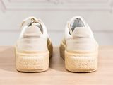 the soles of a pair of white sneakers on a wooden surface