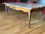 une table au plateau en marbre posée sur un parquet dans un salon