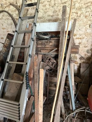 a ladder that is leaning against a wall next to a pile of wood
