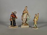 trois figurines représentant des femmes et un homme avec un chien