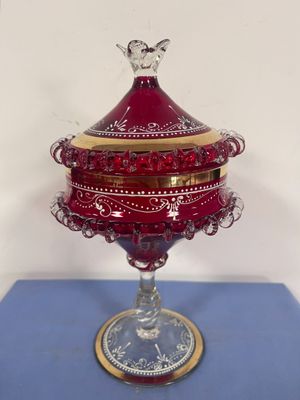 une image représentant une boîte en verre rouge posée sur une table bleue