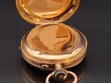 a gold colored pocket watch sitting on a black surface