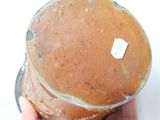 a person holding a brown vase with a tag on it