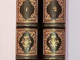 two old books are sitting on a white surface next to each other