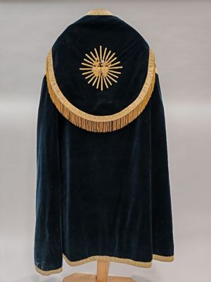 cape en velours bleu avec des franges dorées, posée sur un support, sur fond blanc
