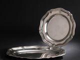 une assiette en argent posée sur une surface noire, avec un fond noir