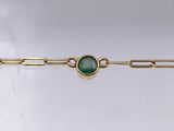 a close up of a gold chain bracelet with a green stone