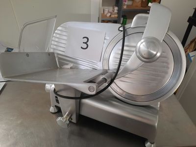an image of a commercial meat slicer on a table
