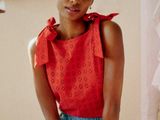 a woman sitting on a bed wearing a red top