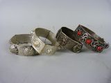 trois bracelets en argent ornés de pierres rouges, posés sur une surface blanche