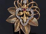 a close up of a gold and diamond flower ring on a black surface