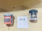 two jars of paint sitting on a table next to a piece of paper