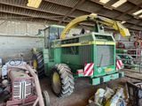un gros tracteur vert garé à l'intérieur d'un bâtiment