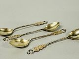 four antique spoons are sitting on a table next to each other