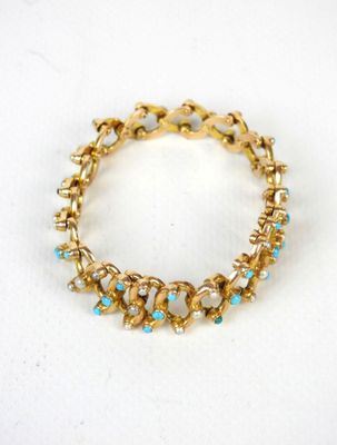 Gros plan sur un bracelet en or orné de pierres bleues