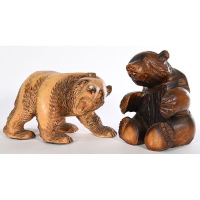 pair of carved wooden bears sitting next to each other on a white surface