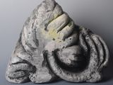 une sculpture représentant une personne assise sur un rocher, la tête entre les mains