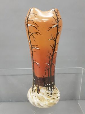 a glass vase that has a picture of a forest on it