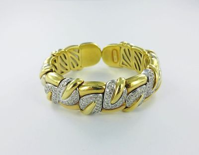 a close up of a gold and diamond bracelet on a white surface