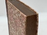 an old book is sitting on a white surface with a white background
