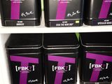 cinq boîtes noires portant des inscriptions violettes, posées sur une étagère