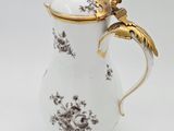 a white and gold coffee pot with a bird on it