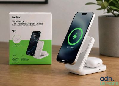 une photo représentant un téléphone et un chargeur posés sur une table, avec une plante en arrière-plan
