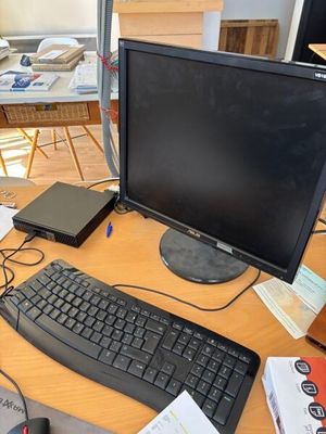 a desk with a computer, keyboard, mouse, and other items on it